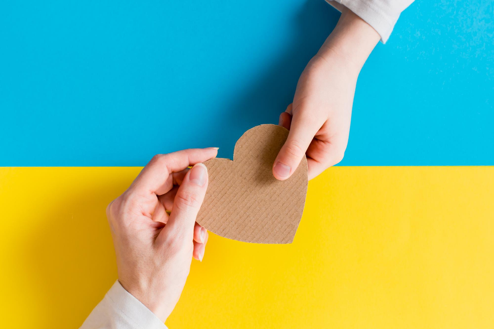 concept is no war ukraine childrens womens hands hold cardboard heart against background ukrainian flag top view